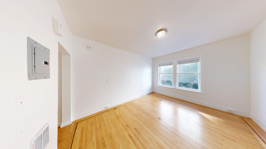 A room with a window and a wooden floor.
